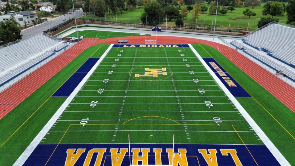 Aerial view of a green football field with yellow and blue markings.