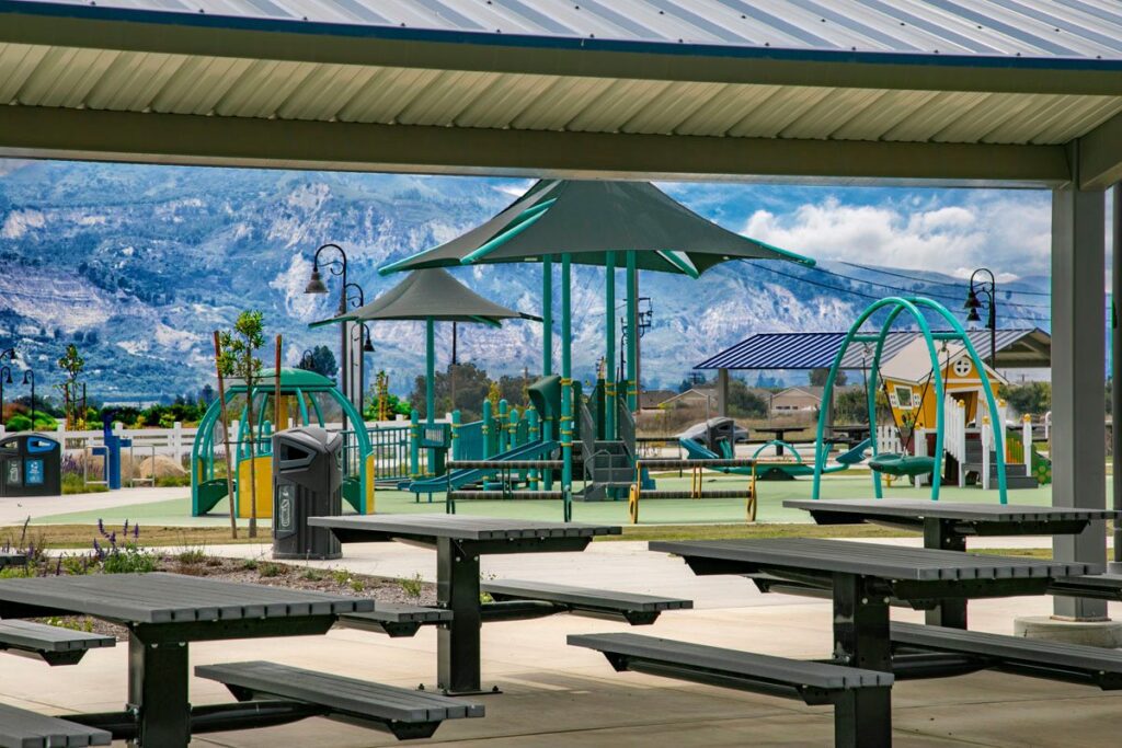 A colorful playground set under a covered pavilion with benches.