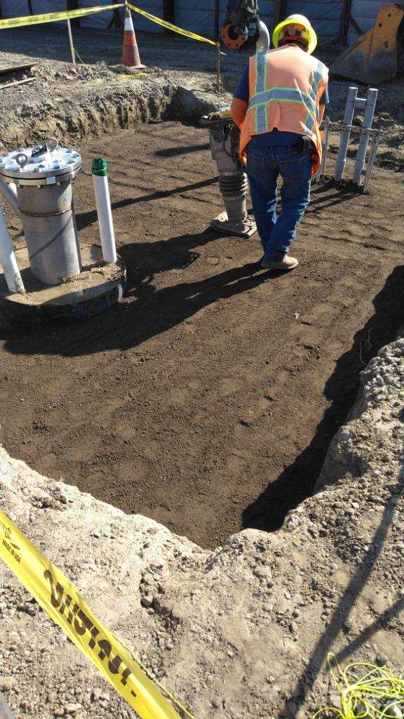 Freshly raked soil in a garden bed with a person standing nearby.