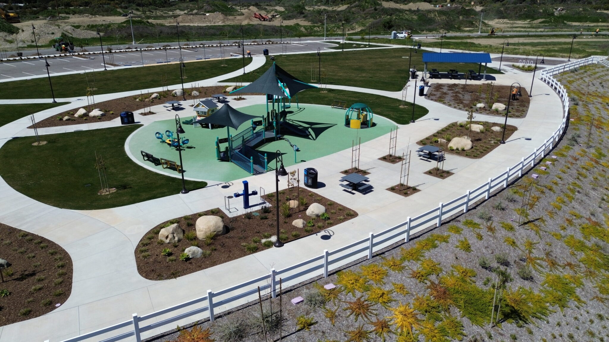 A colorful playground with slides and swings in a fenced area on a sunny day.