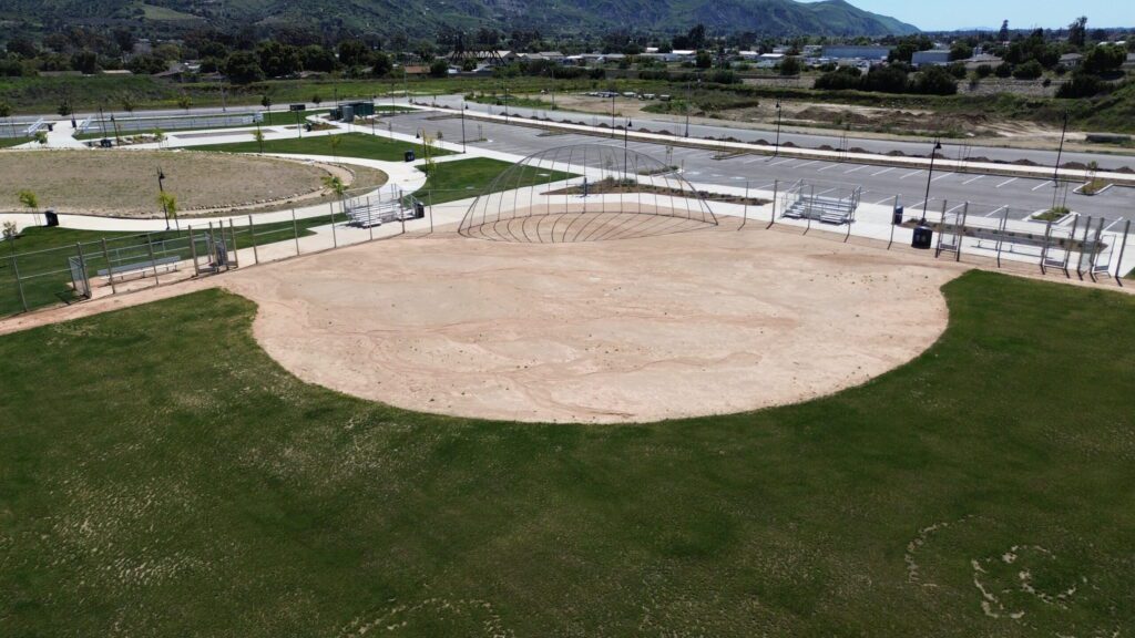 A baseball field with dirt infield and green grass outfield.