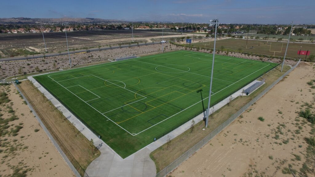 A green soccer field under construction in a barren area.