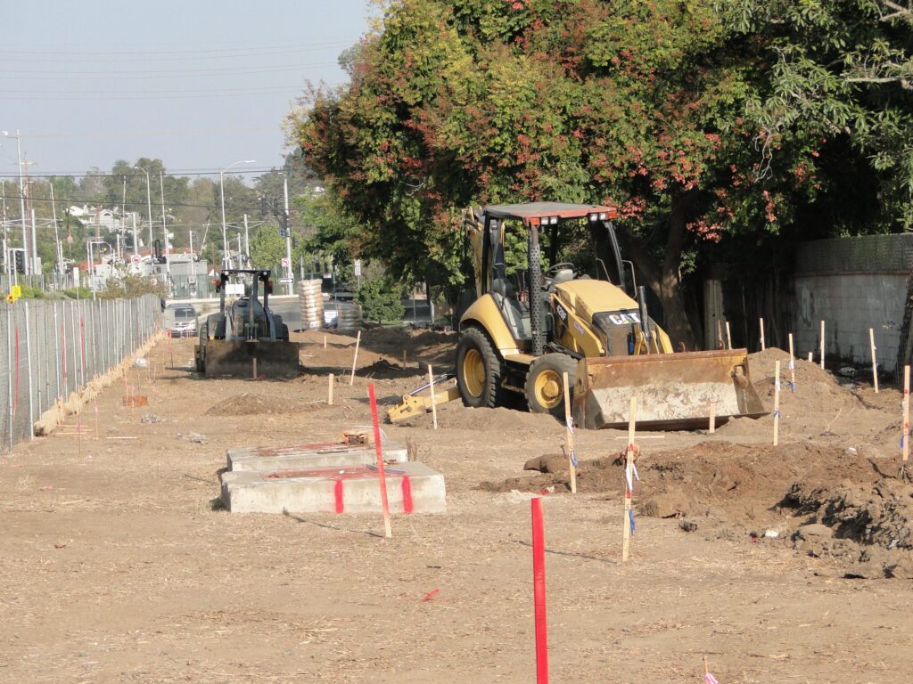 Construction site with machinery and marked ground.