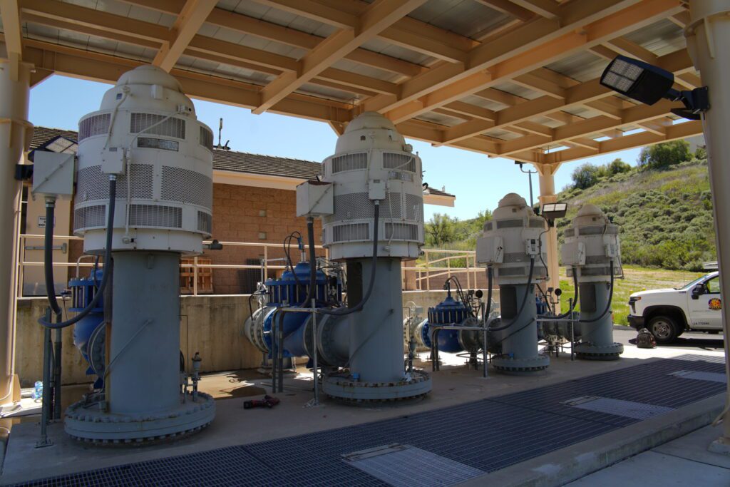 Industrial machinery setup under a wooden shelter outdoors.