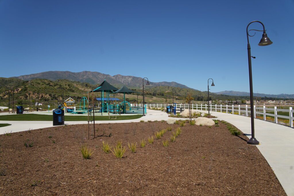A playground with swings and a clear mountain backdrop under a blue sky.