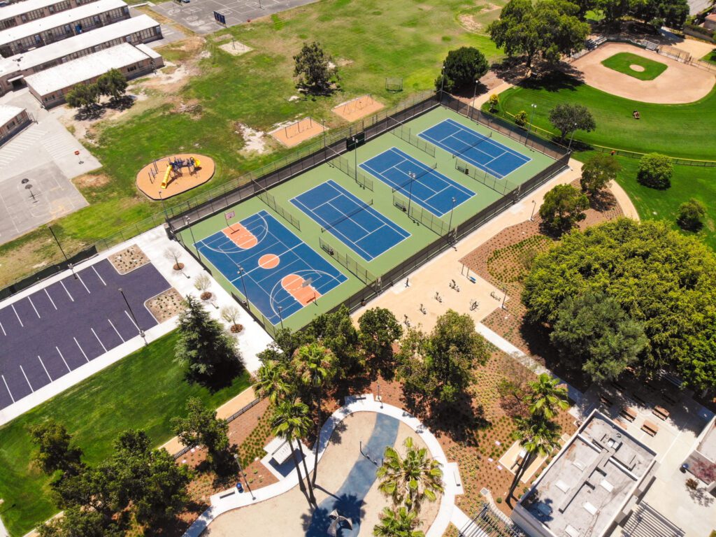 Aerial view of a community park with tennis courts and a playground.