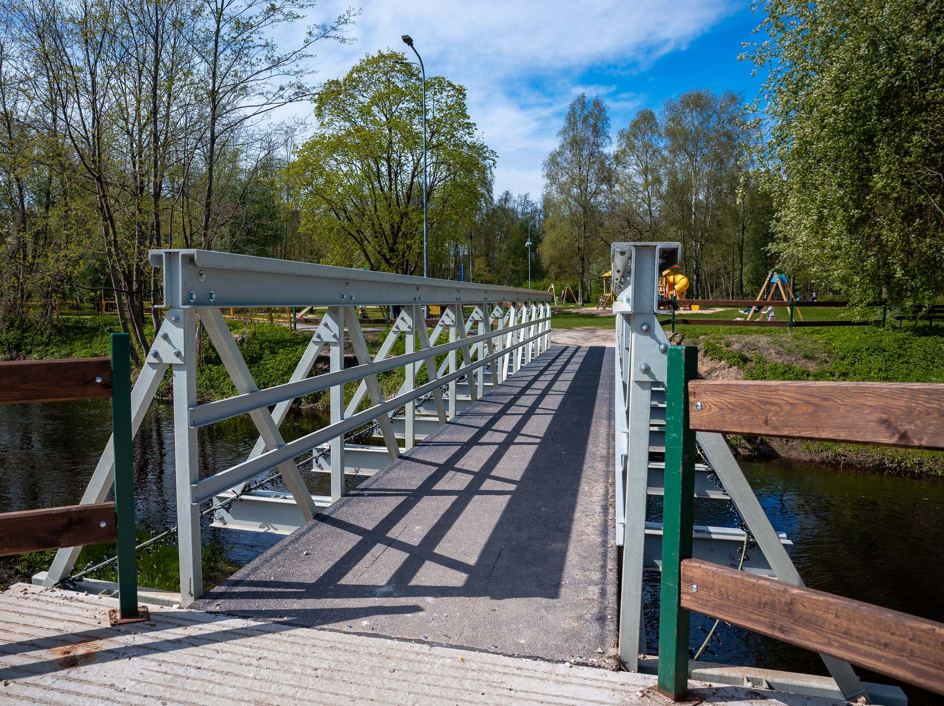 Sunny park with metal footbridge