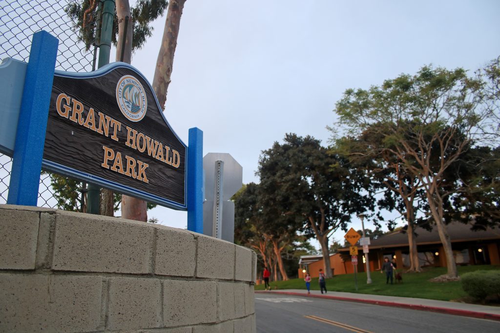 Entrance sign of Grant Bowl Park with clock and palm trees.