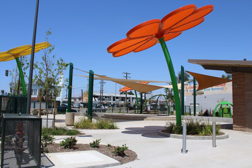 Large orange flower sculptures in a sunny outdoor park area.