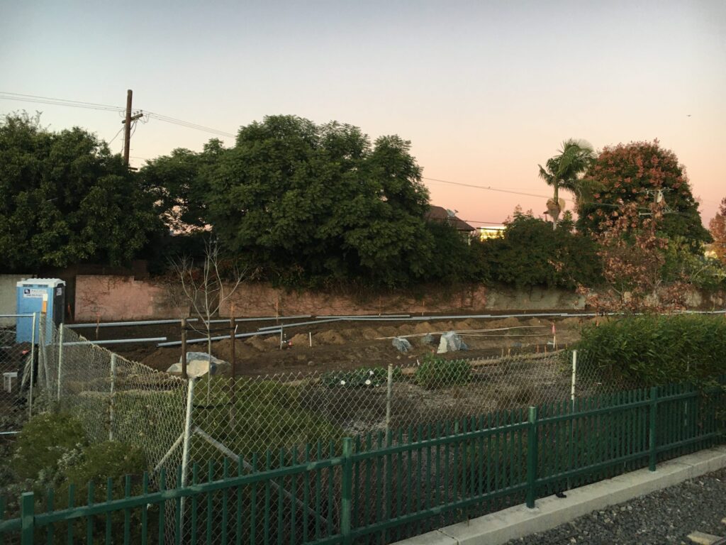 A serene outdoor scene with trees and a fenced area at dusk.