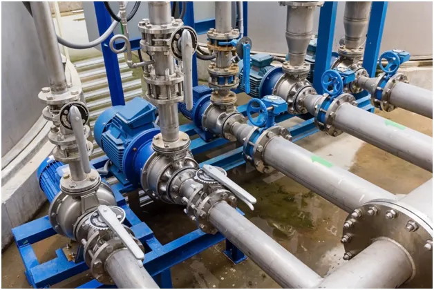 Industrial piping system with valves and blue pumps.