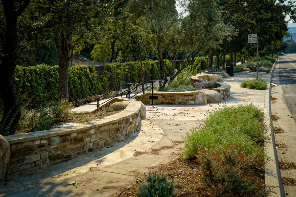 A winding stone bench path in a peaceful garden with trees and greenery.