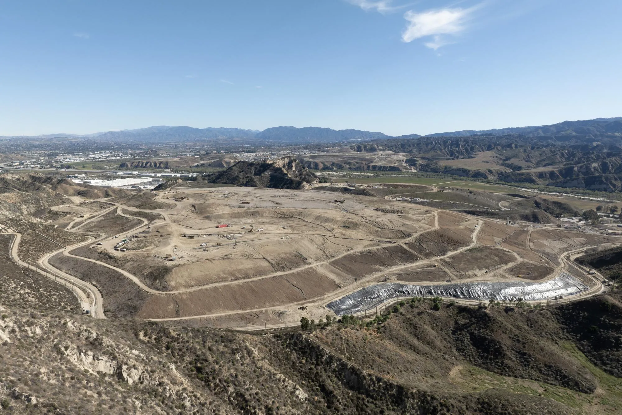 Vast open landscape with winding roads and distant mountains under a clear sky.