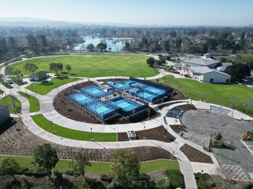 Aerial view of a large outdoor swimming pool complex in a park.