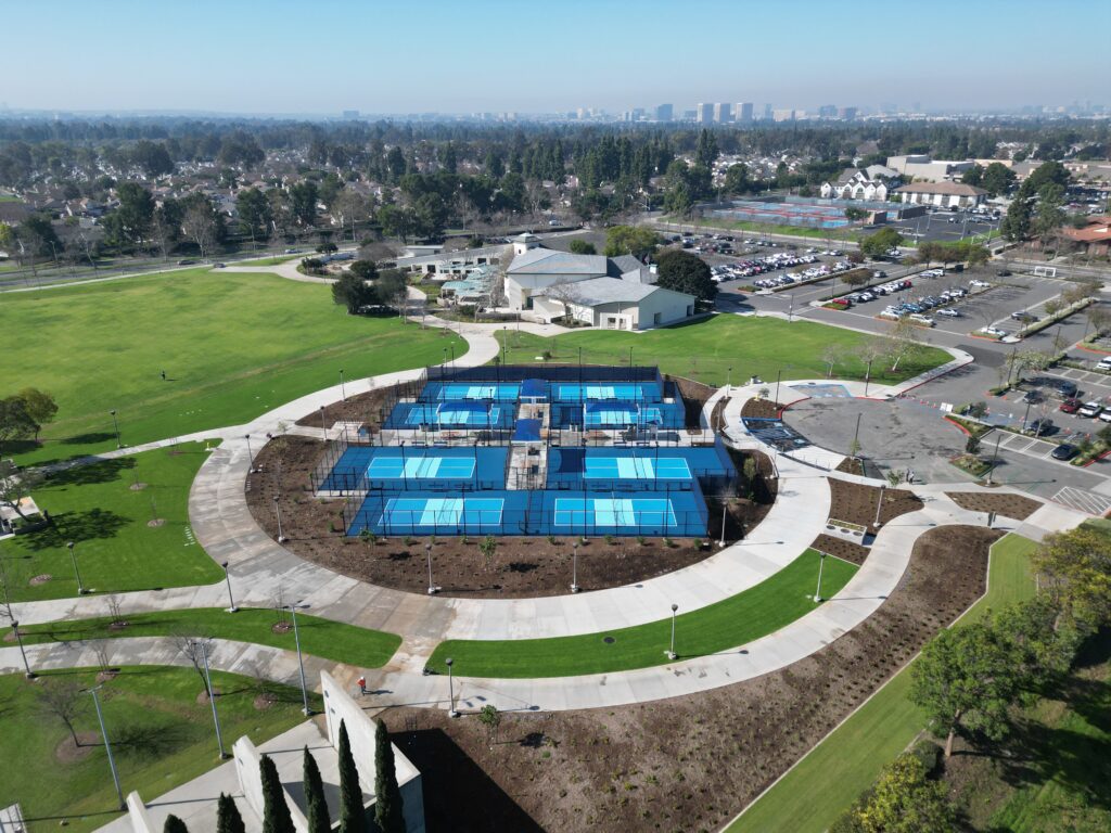Aerial view of a blue outdoor swimming pool complex in a park.