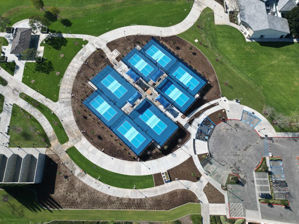 A symmetrical complex of blue-roofed buildings surrounded by curved pathways and green lawns.