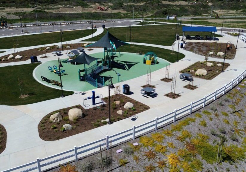 A colorful playground with slides and swings in a fenced area on a sunny day.