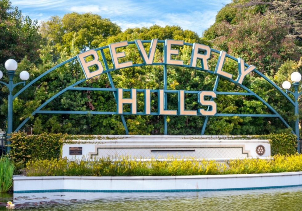 The iconic Beverly Hills sign surrounded by greenery and blue sky.